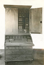 Tall writing desk with drawers, cubbies, and cabinet with open door.